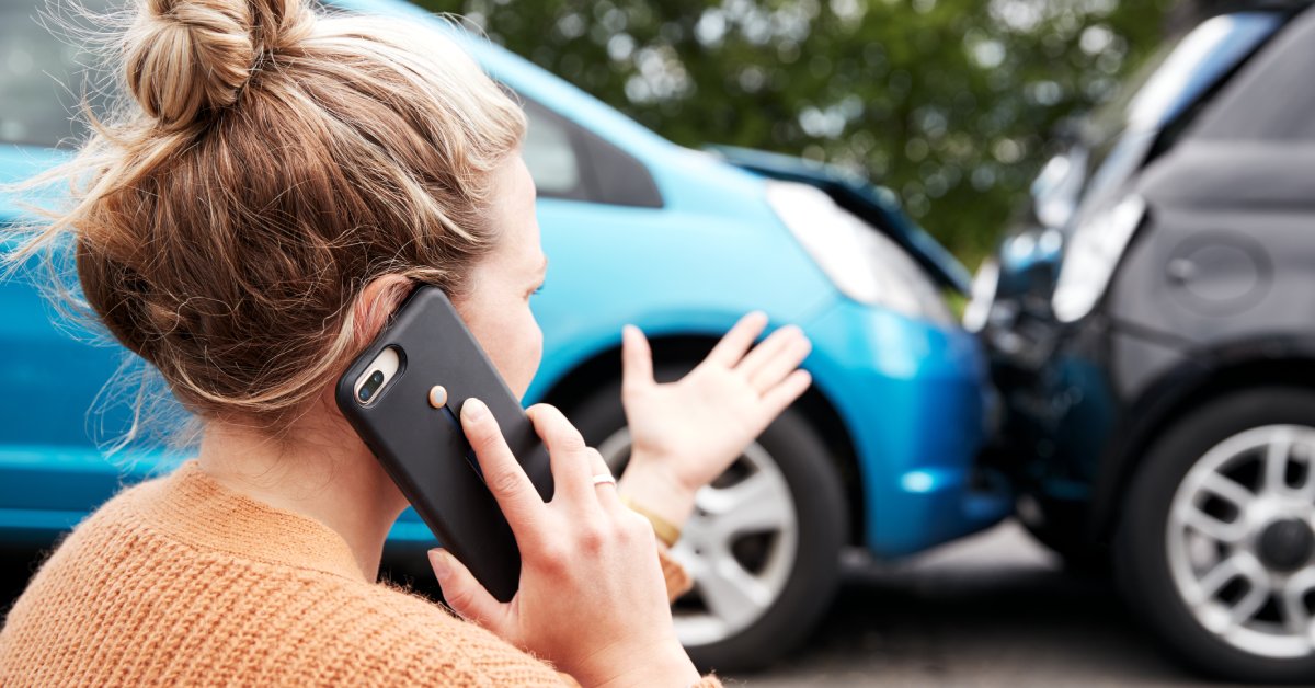 The back of a person with blonde hair talking on the phone. They are gesturing at a minor vehicle collision.
